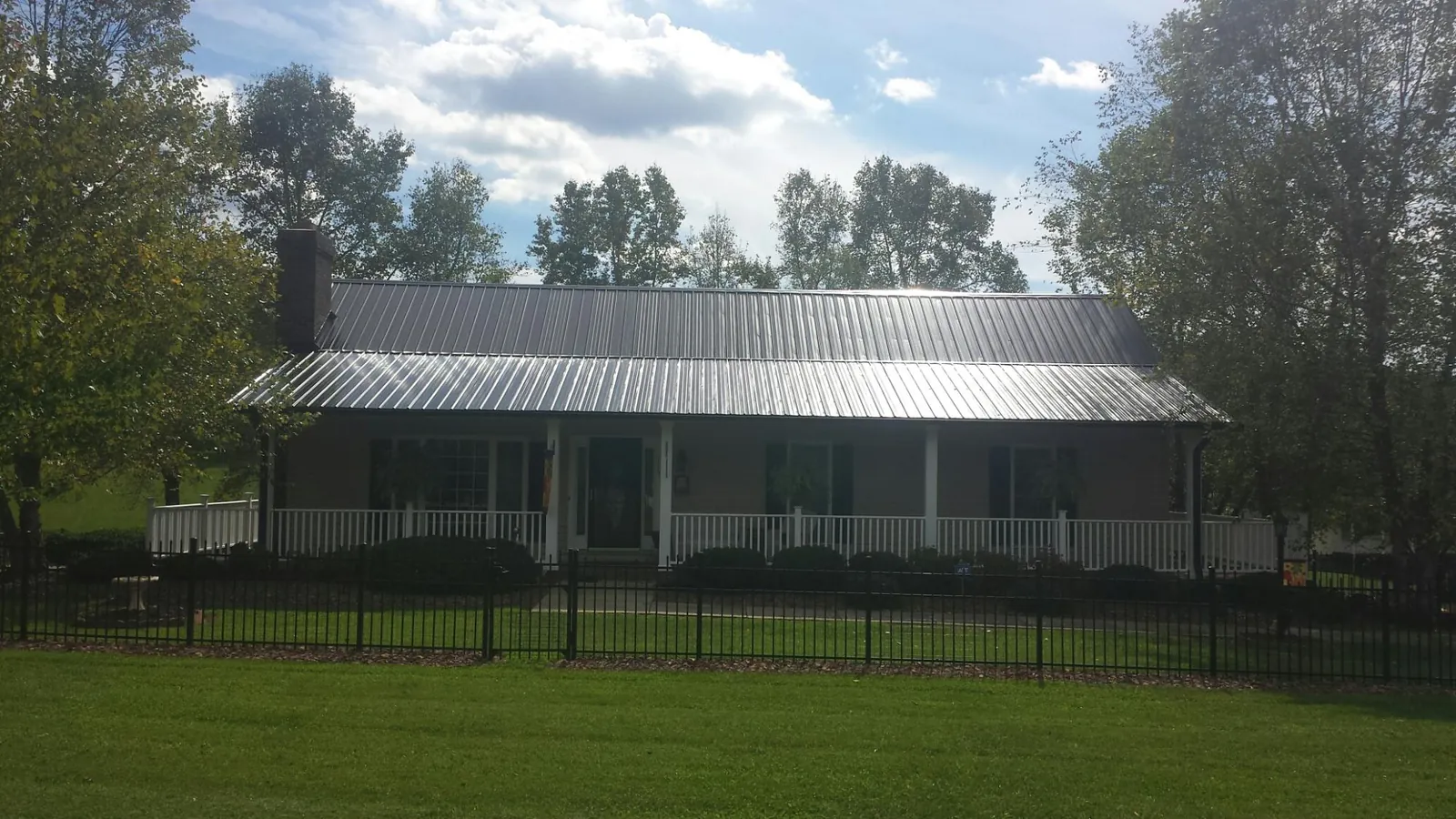 Gray metal roof on a brick ranch with a full width front porch — Gutter Guard Installation work by our crew in Kincaid