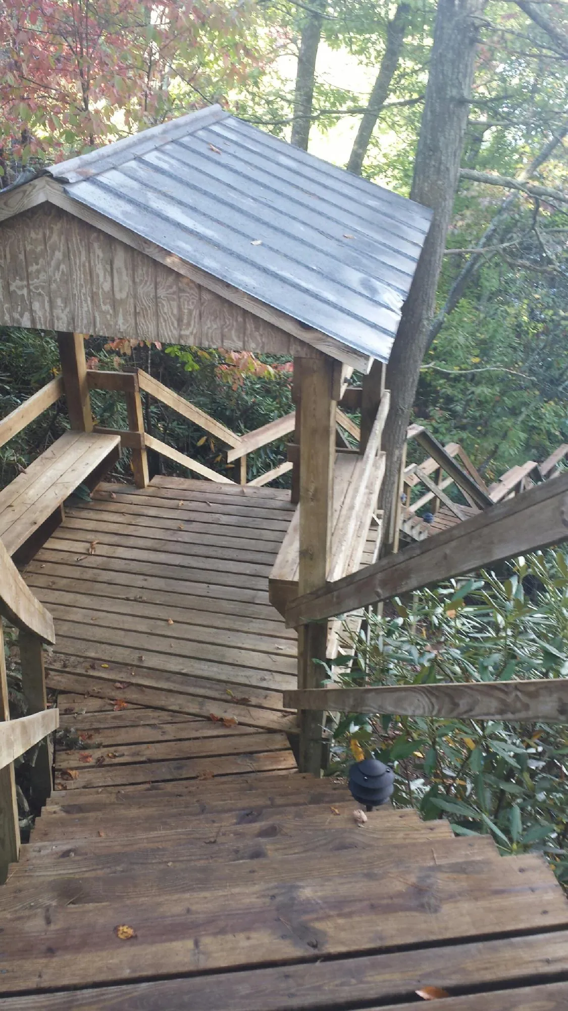 Metal roofed shelter over wooden steps on a wooded walkway — Skylight Repair & Installation work by our crew in Kincaid