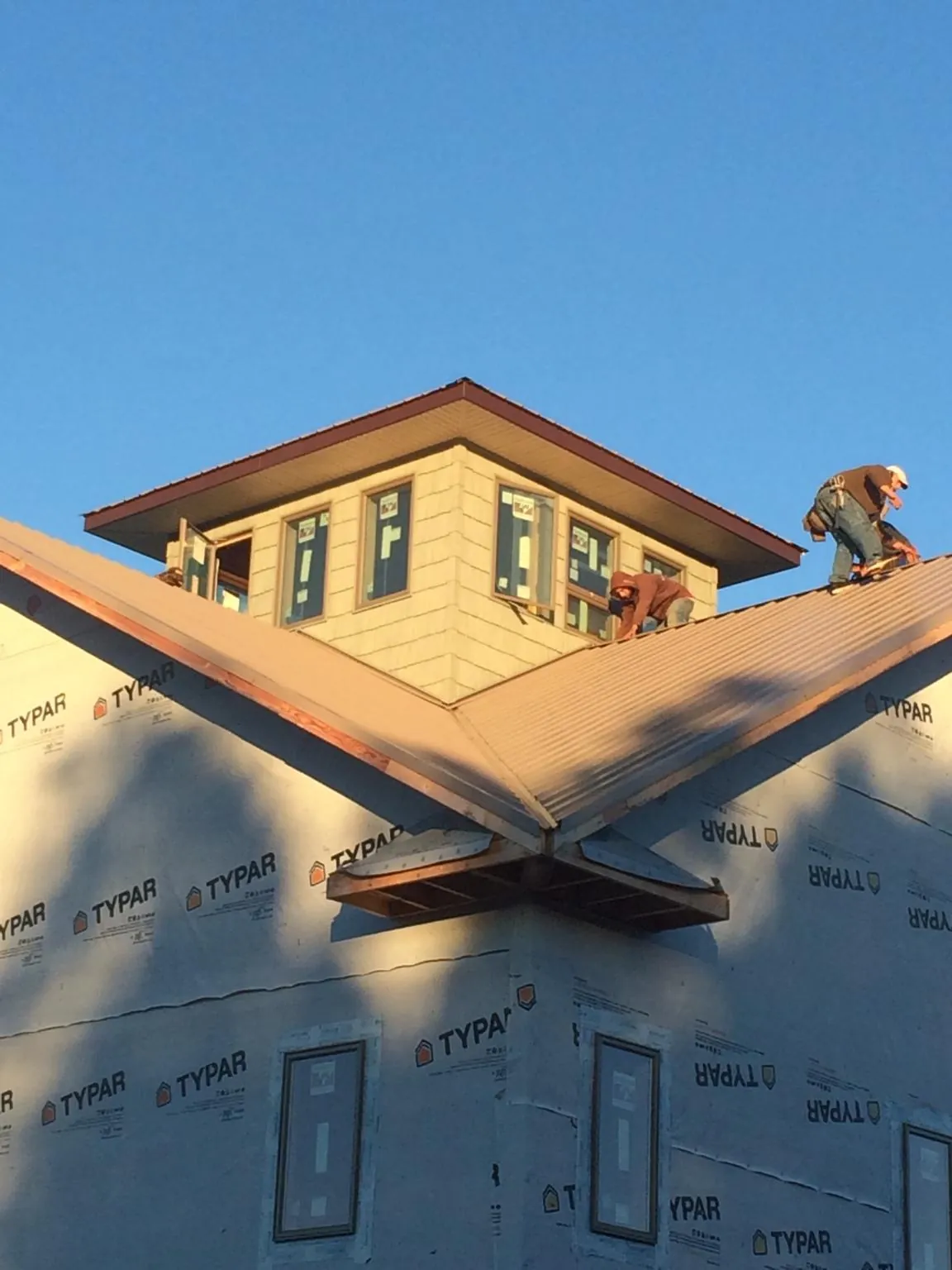 Roofers working around a rooftop cupola on a new metal roof at sunset — Roof Waterproofing in Kincaid by Roofing Brothers